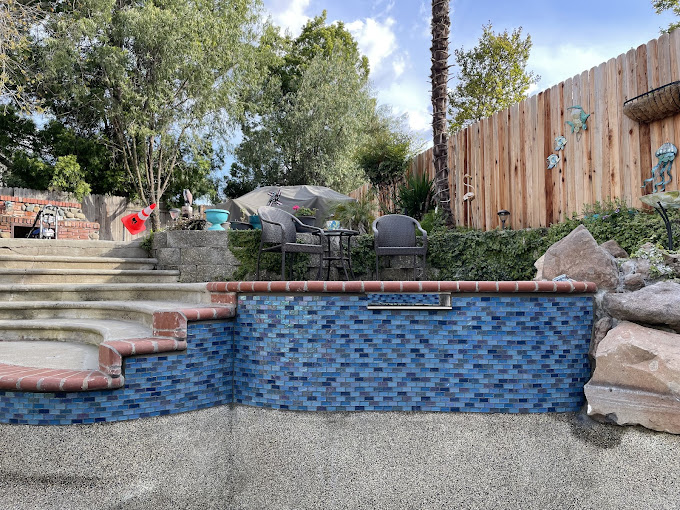 A blue and red tiled swimming pool next to a wooden fence