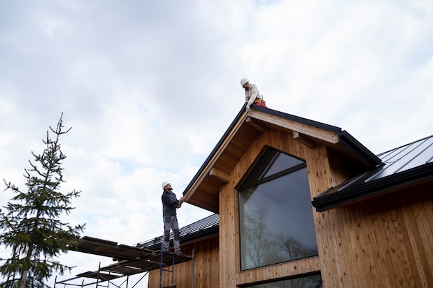 A man standing on top of a roof next to a tree