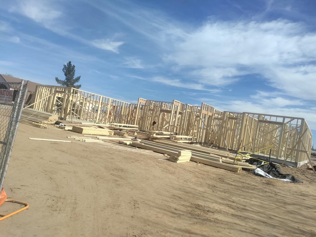 A construction site with a fence and a building in the background