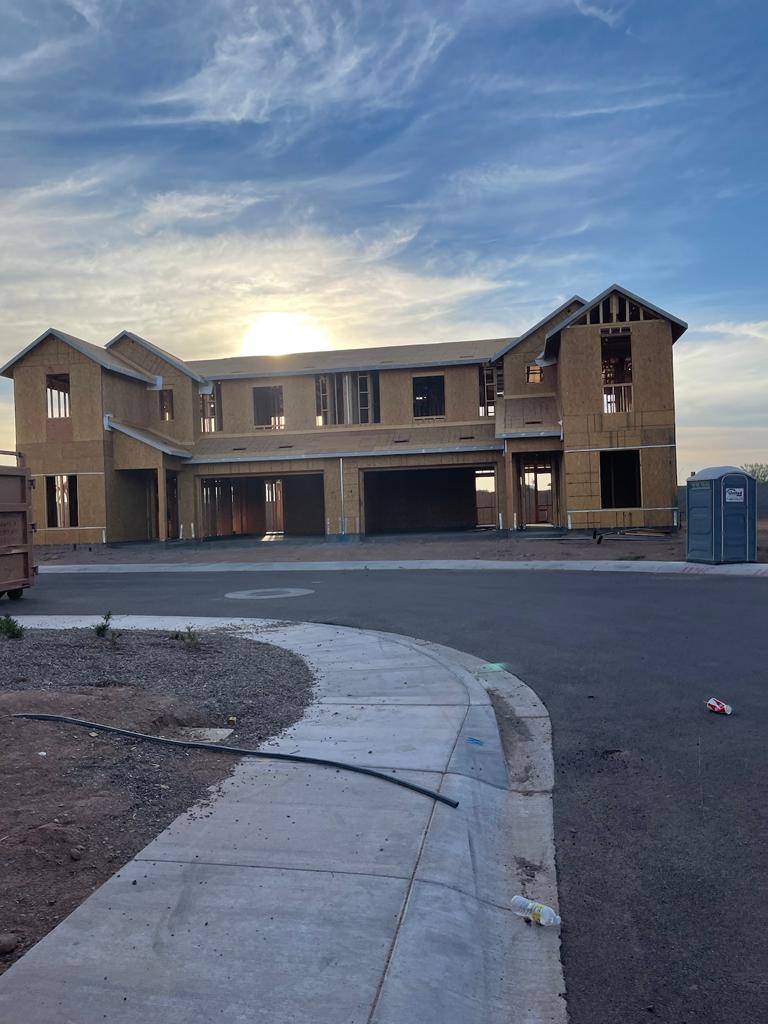 A house under construction with the sun setting in the background