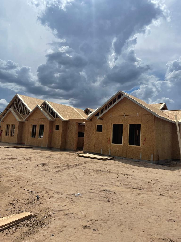 A row of houses under construction under a cloudy sky