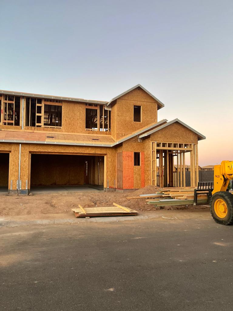 A large tractor parked in front of a house under construction